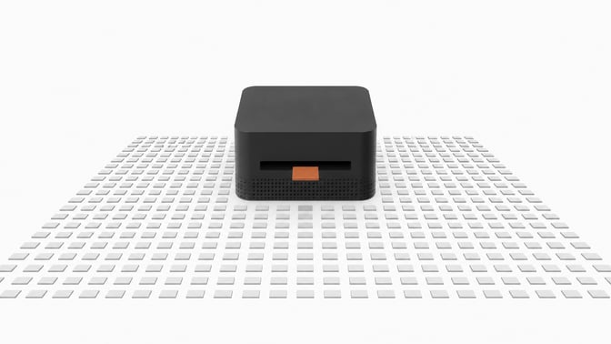 A thick, square desktop computer sits at the center of a vast, precise grid of small blank tiles, with a single accented tile entering its front slot to represent a local AI inference query.