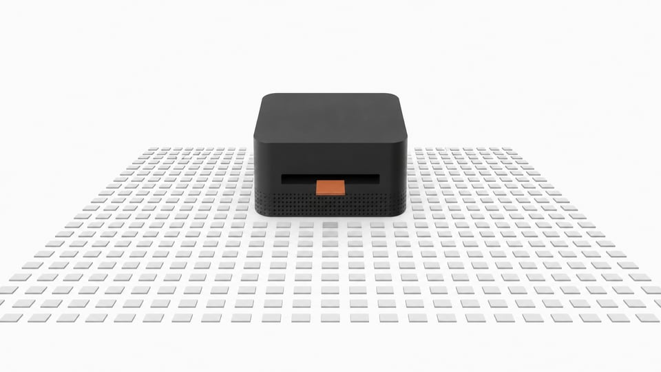 A thick, square desktop computer sits at the center of a vast, precise grid of small blank tiles, with a single accented tile entering its front slot to represent a local AI inference query.