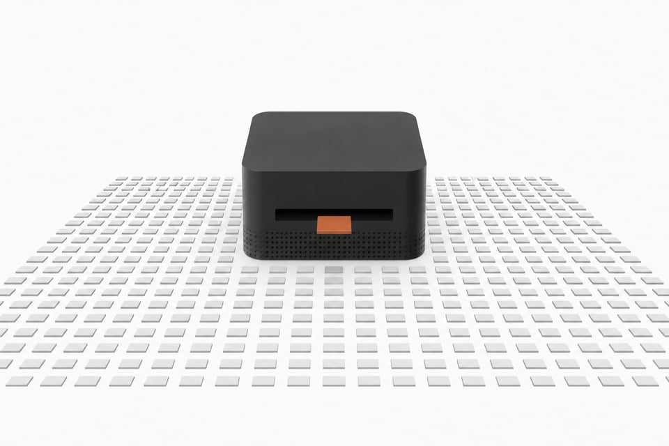A thick, square desktop computer sits at the center of a vast, precise grid of small blank tiles, with a single accented tile entering its front slot to represent a local AI inference query.